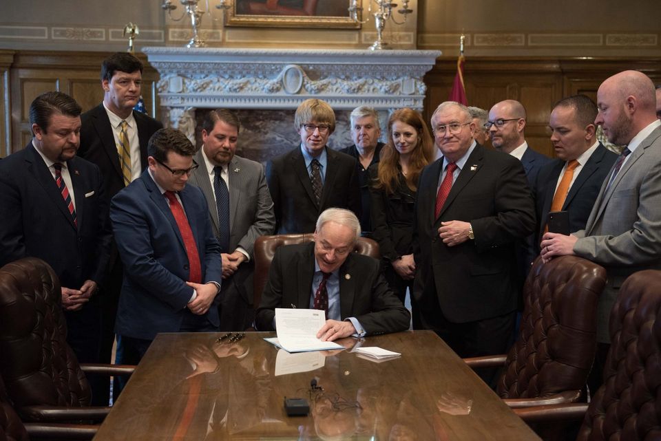 The signing of Arkansas's Solar Access Act in 2019, with Douglas Hutchings among the advocates standing behind the desk